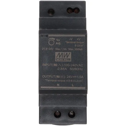 Zdjęcie przedstawia zasilacz marki Mean Well z oznaczeniami technicznymi na przedniej stronie, w tym parametrami wejściowymi i wyjściowymi. Urządzenie ma prostokątny kształt i ciemny kolor, z widocznymi śrubami montażowymi na górze i dole.