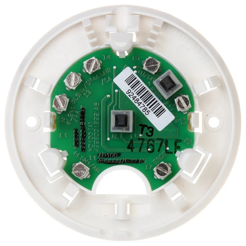 Zdjęcie przedstawia okrągłą, białą podstawę do czujnika dymu z widoczną zieloną płytką drukowaną i metalowymi złączami. Na płytce znajdują się oznaczenia techniczne oraz naklejka z kodem kreskowym.
