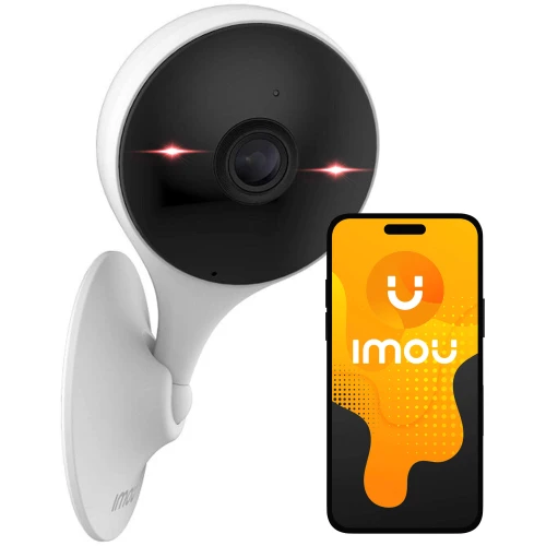 Na zdjęciu znajduje się biała kamera IP o nowoczesnym designie, zamontowana na ścianie. Obok kamery widoczny jest smartfon z logo "Imou" na ekranie.