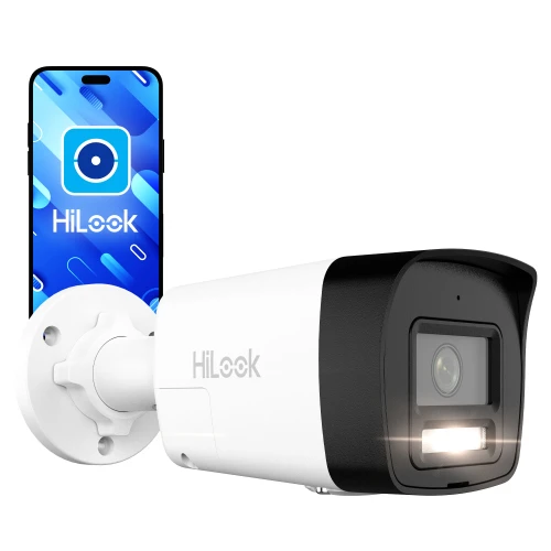 Na zdjęciu znajduje się biała kamera IP HiLook z czarnym frontem, zamontowana na uchwycie ściennym. Obok kamery widoczny jest smartfon z logo HiLook na ekranie.
