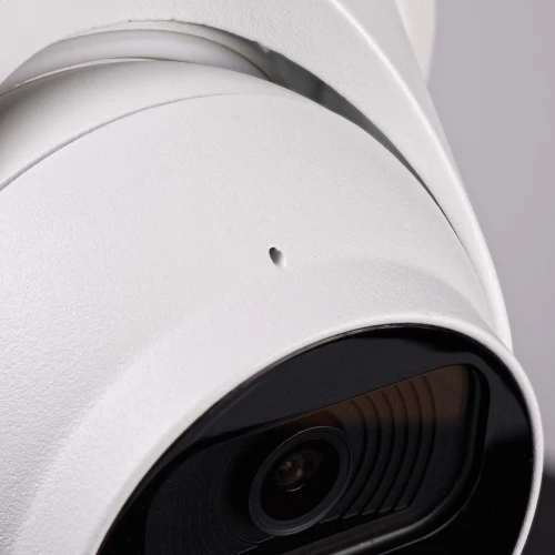 Zbliżenie na białą kamerę kopułową z widocznym obiektywem i detalami obudowy. Kamera ma nowoczesny design i jest przeznaczona do monitoringu.