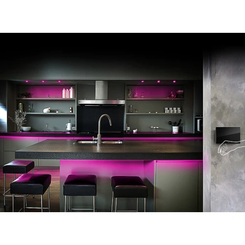 Sterownik gestem Fibaro Swipe jest zamontowany na ścianie nowoczesnej kuchni, umożliwiając kontrolę oświetlenia LED o różowym odcieniu. Produkt jest elegancki i dyskretny, idealnie komponując się z minimalistycznym wystrojem wnętrza.