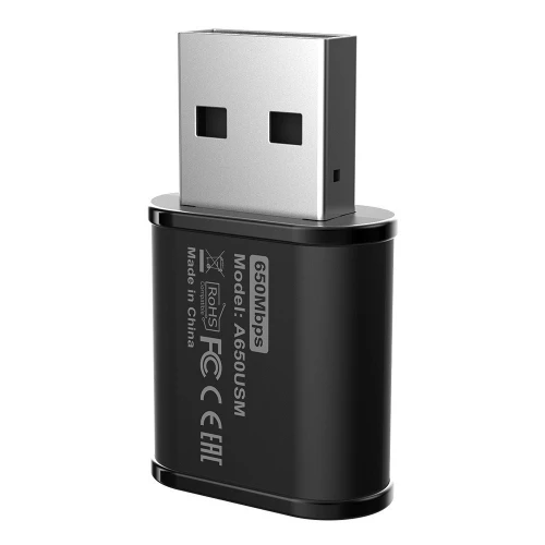 Na zdjęciu znajduje się czarny adapter USB z oznaczeniami technicznymi, takimi jak "650Mbps" i "AC650U". Adapter ma prostokątny kształt z metalowym złączem USB na górze.