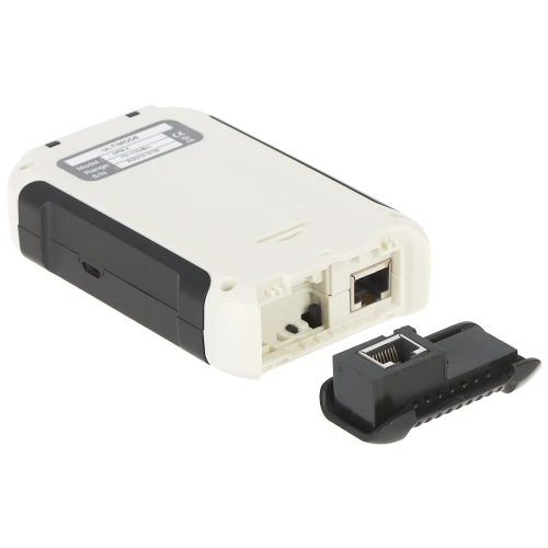 Na zdjęciu znajduje się biało-czarny tester okablowania z widocznymi portami RJ-45 oraz osobnym terminatorem. Urządzenie jest ustawione na białym tle, co podkreśla jego detale i konstrukcję.